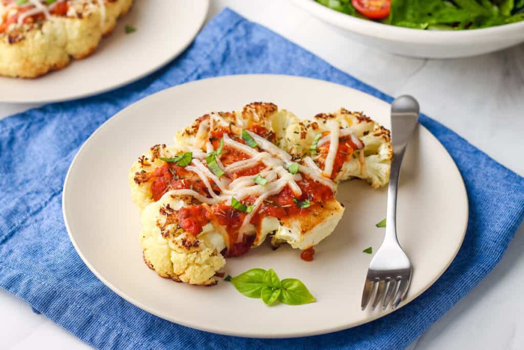 Cauliflower steak smothered in pizza sauce with melted cheese.