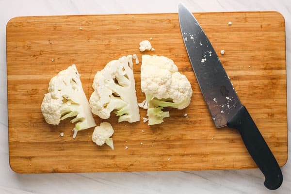 Half a cauliflower sliced into wedges on a cutting board.