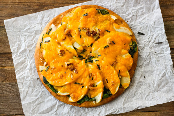 Overhead view of baked pita pizza on a piece of parchment.