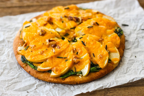 pita pizza on a piece of parchment on a wooden table.