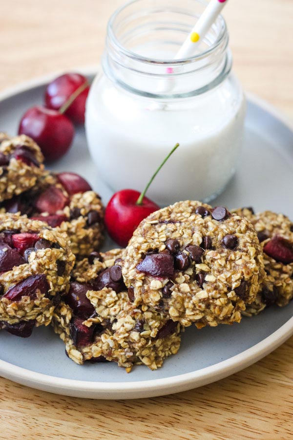 Oat cookies on a blue plate with a small glass of milk.