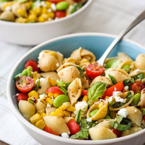 Two bowls of chickpea pasta in blue bowls on a white napkin.