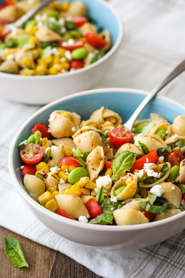 Two bowls of chickpea pasta in blue bowls on a white napkin.