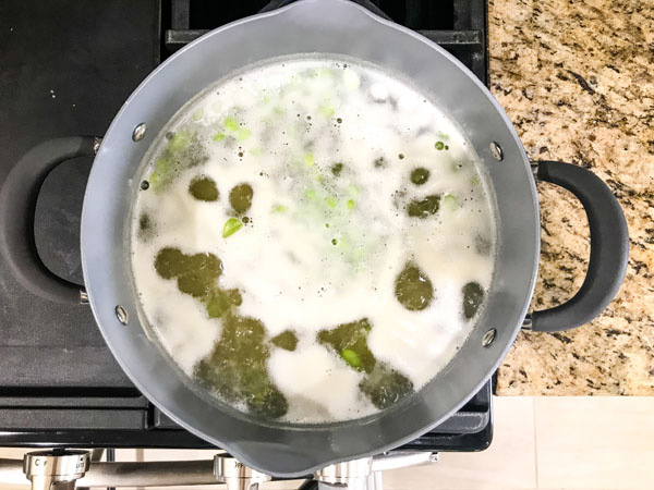 Chickpea pasta in a pot of boiling water with foam on top.