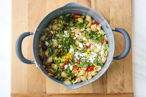 Corn and Tomato Chickpea Pasta in a large cooking pot on a cutting board.