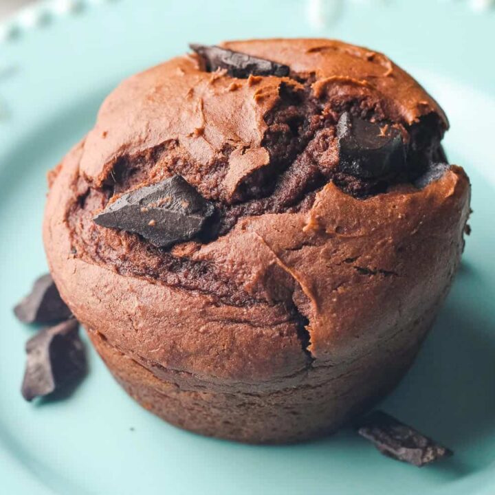 Closeup of big chocolate chunks on a muffin on a plate.