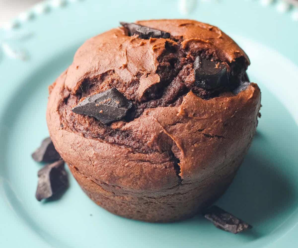 Closeup of big chocolate chunks on a muffin on a plate.