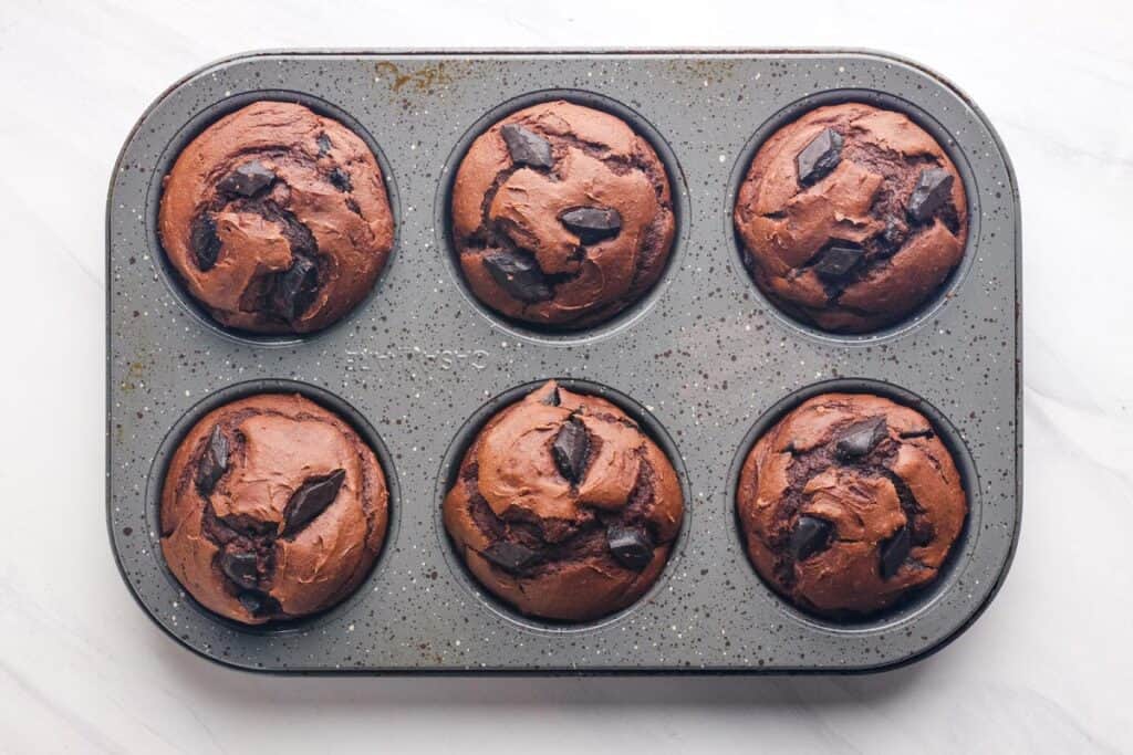 Overhead view of chocolate chunks in baked muffins.