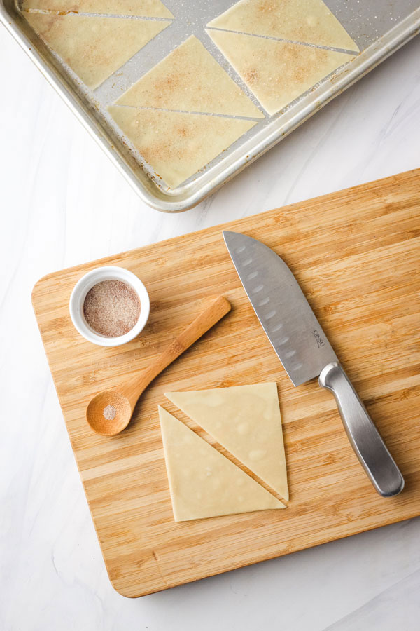 Wonton wrapper on a cutting board sliced in half.