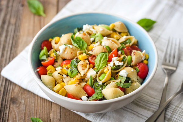 Corn and Tomato Chickpea Pasta in a blue bowl on a white napkin.