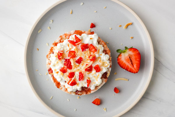 Rice cake topped with cottage cheese and strawberries on a blue plate.