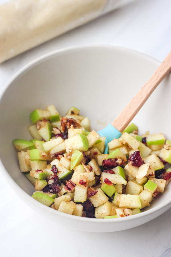 A small bowl with chopped dried cranberries, pecans, and apple pieces.