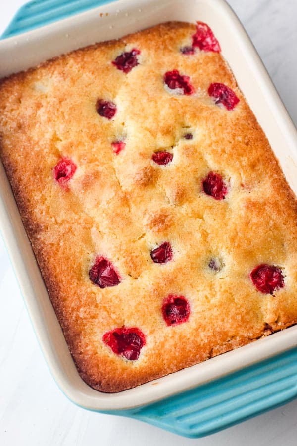 Baked cranberry orange snack cake in a small blue baking dish.