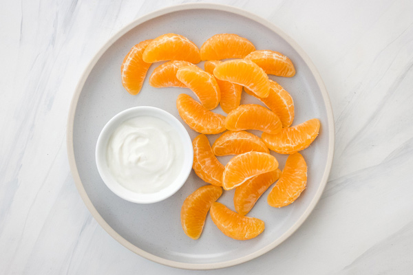 Plate with a small bowl of yogurt and clementine wedges.