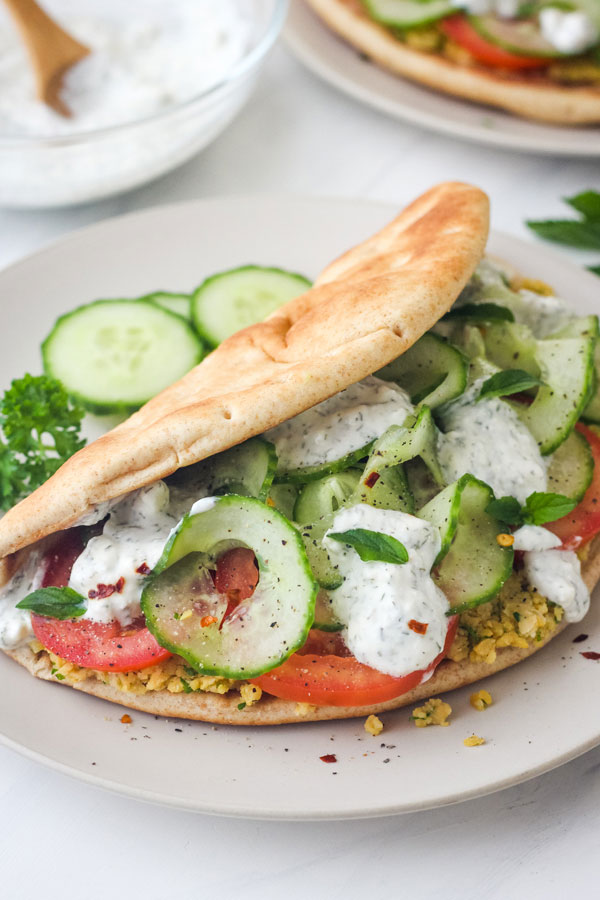 Close up of stuffed pita sandwich on plate.