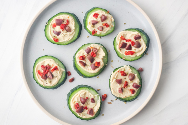 Plate of cucumber slices topped with hummus.