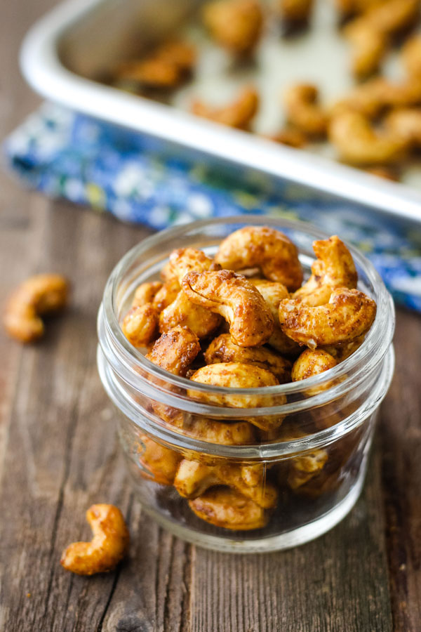 Spiced cashews in a small mason jar on a wood table.