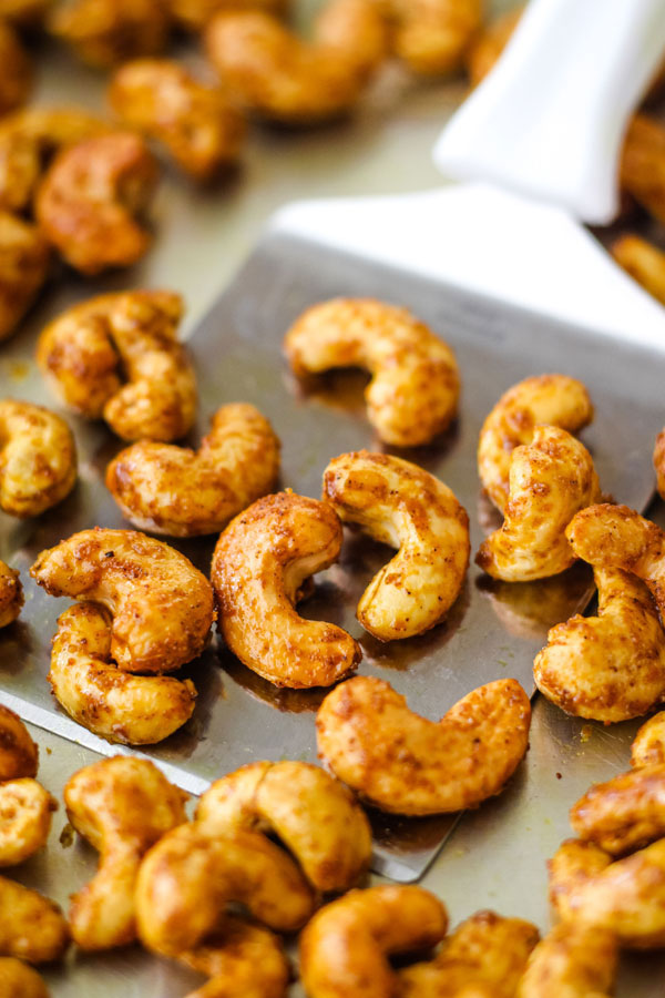 Toasted curry spiced cashews on a metal spatula.