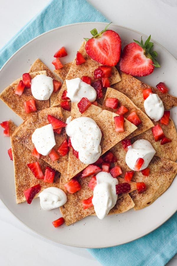 Plate of cinnamon chips topped with whipped cream and chopped strawberries.