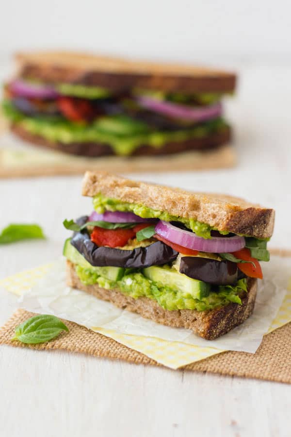 Half a broiled eggplant sandwich on a piece of parchment.