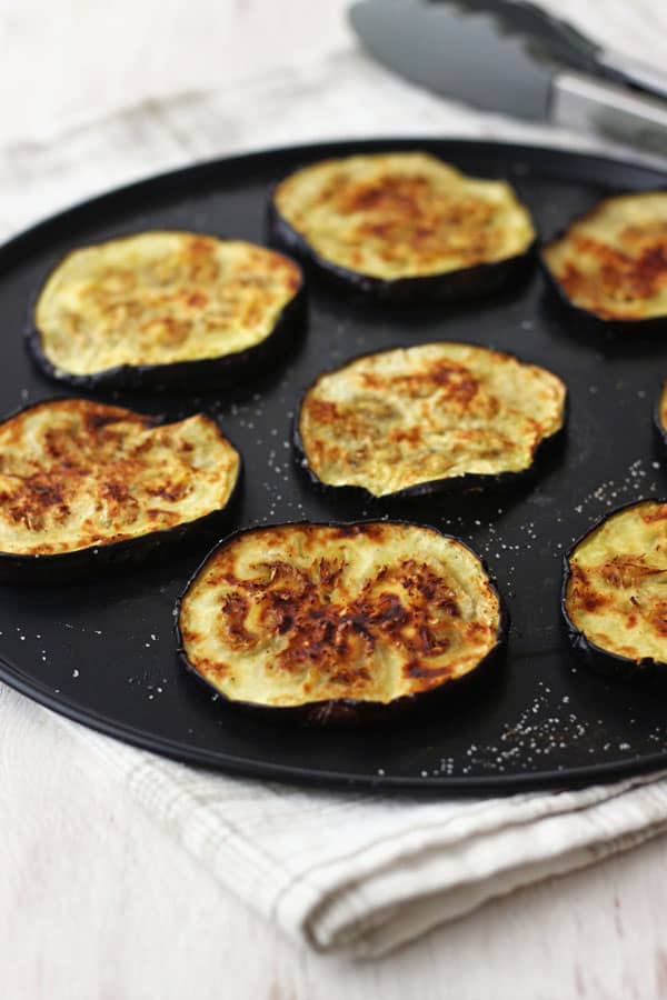 Cooked eggplant slices on a pizza pan.