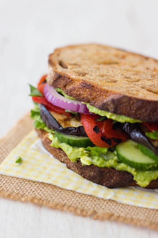 a sandwich stacked high with layers of vegetables on a yellow napkin