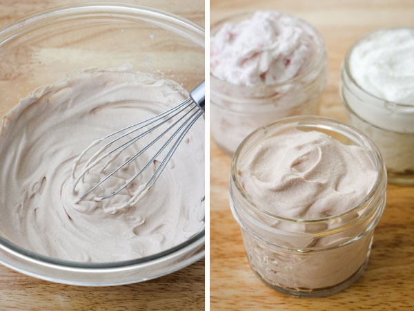 A glass bowl of chocolate whipped cream and small mason jars with chocolate, strawberry, and vanilla whipped cream.