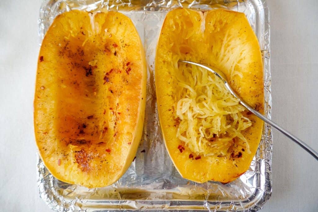 Roasted spaghetti squash halves on a small foil lined pan.