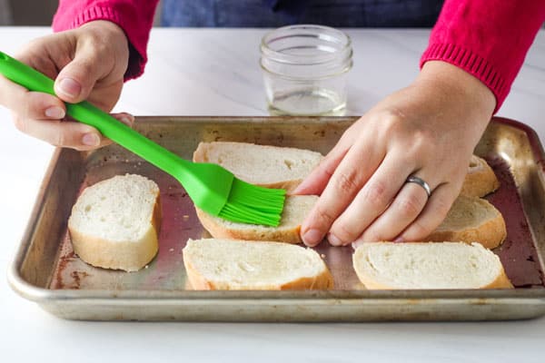 Person brushing oil on bread slices.