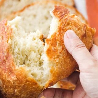 Hands tearing a loaf of fresh bread.