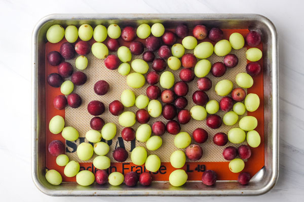 Frozen red and green grapes on a quarter sheet pan.