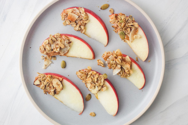 Plate of apple wedges topped with granola.