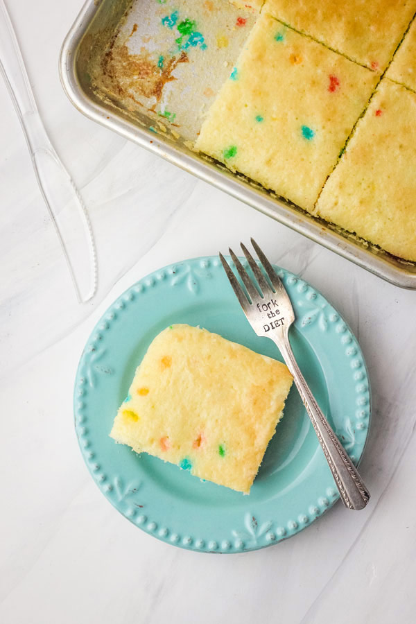 Piece of cake on a blue plate with a small fork.