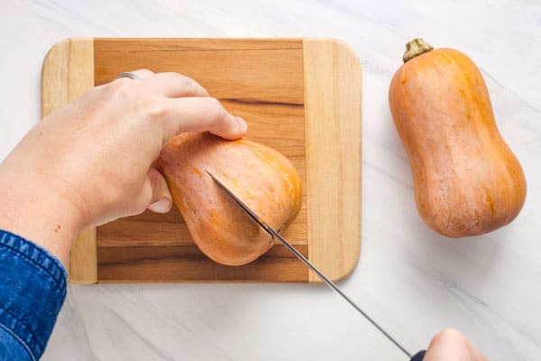 Person cutting through middle of squash with a sharp knife.