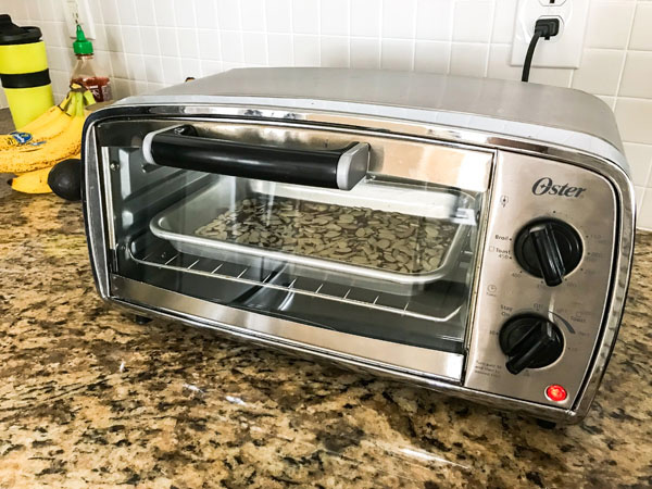 Sliced almonds toasting in a small toaster oven. 