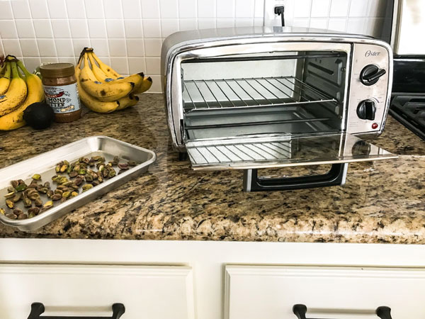 Countertop with toaster oven and small sheet pan with pistachios.