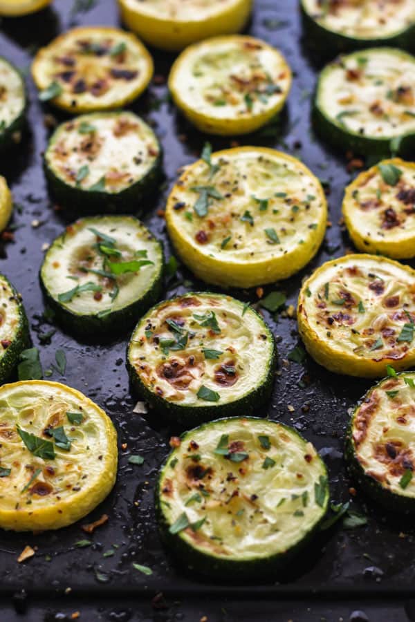 Broiled zucchini and squash rounds on a roasting pan.