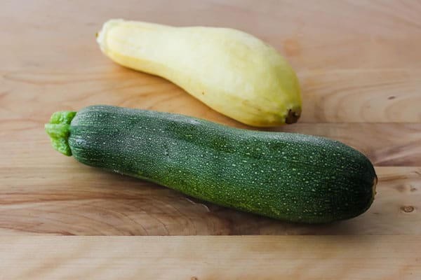 Fresh zucchini and yellow summer squash on a cutting board.