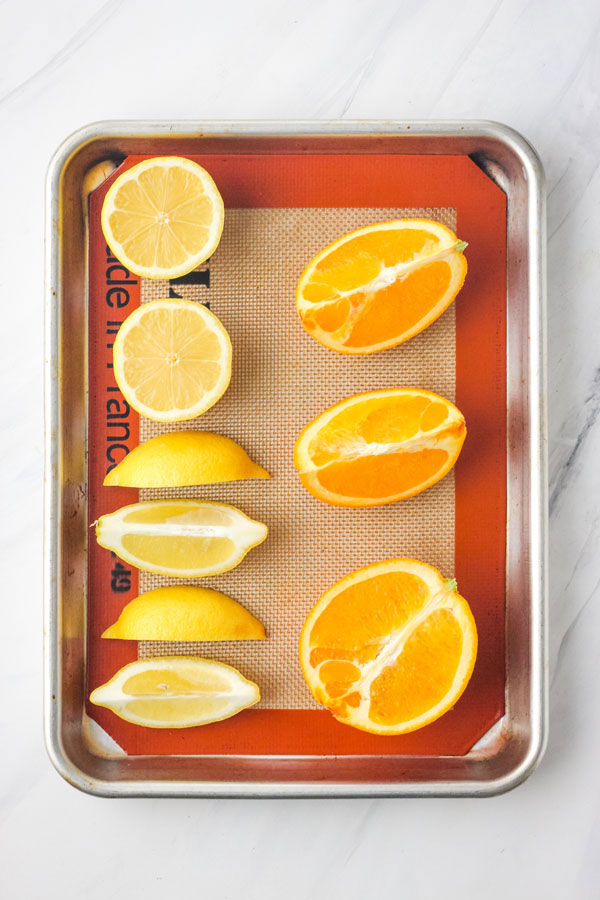 Lemon and orange wedges and halves on a baking sheet lined with a silicone mat.