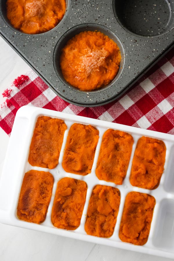 Overhead view of ice cube tray and muffin tin with frozen pumpkin.