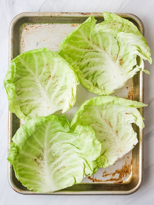 Seasoned cabbage leaves on a sheet pan.