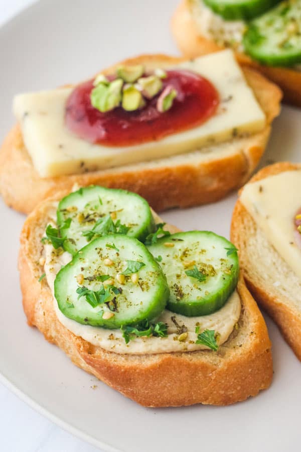 Closeup of crostino topped with hummus and cucumber slices.