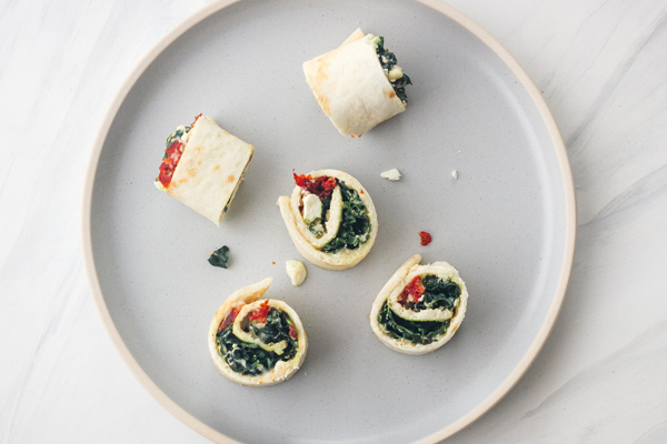 Hummus and kale pinwheels on a blue plate.