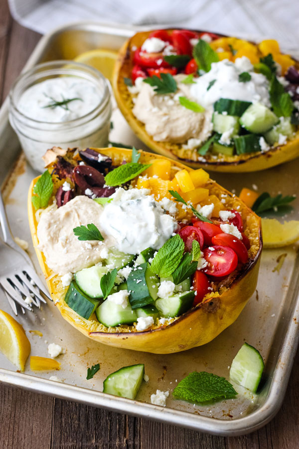 Stuffed spaghetti squash with toppings and a jar of tzatziki sauce.