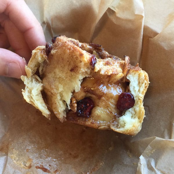 Flaky pastry and gooey interior of a caramel harvest roll filled with apples and dried cranberries.