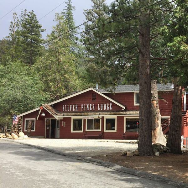 A large red barn-like building set among large trees.