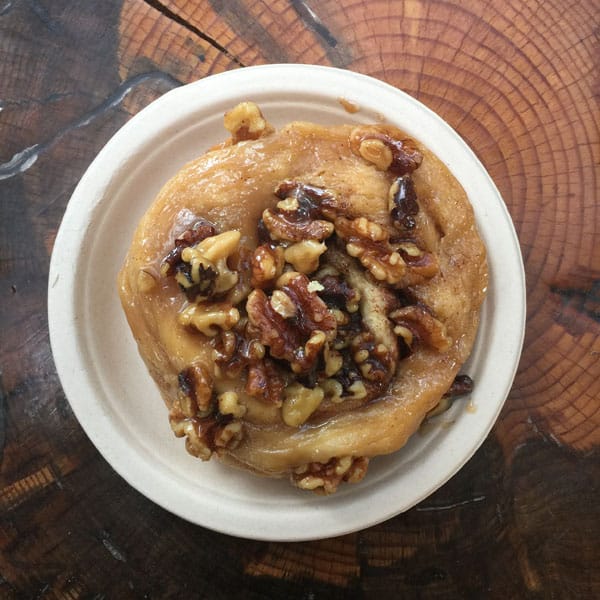 Sticky bun loaded with nuts on a wood table.