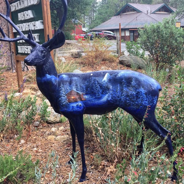 Deer painted with a blue snowy cabin landscape.