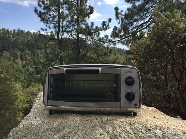 Toaster oven on a boulder in the forest.