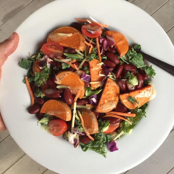 A white plate with chopped salad, baked sweet potato slices and kidney beans.